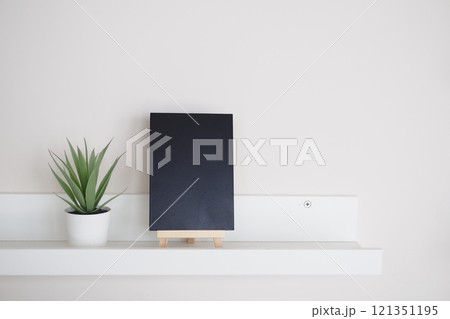 Stylish Minimalist Home Decor Featuring a Black Notebook and a Green Plant Stylish Minimalist Home Decor Featuring a Black Notebook and a Green Plant 121351195