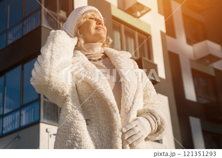 Elegant senior woman wearing winter clothes adjusting her hat outdoors 121351293