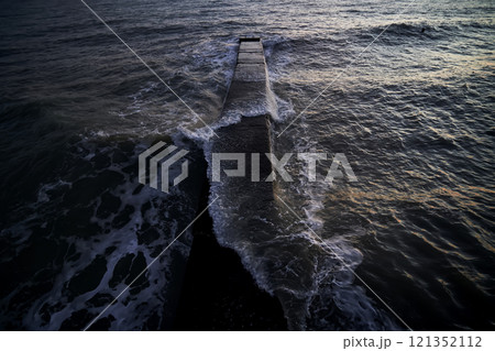 Landscape with a stone pier and raging waves in the sea. Landscape with a stone pier and raging waves in the sea. 121352112