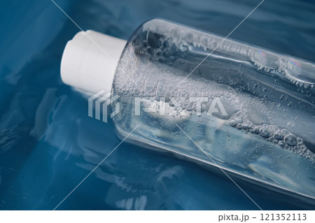 Bottle with cosmetic gel for face and body on blue background in water. Bottle with cosmetic gel for face and body on blue background in water. 121352113