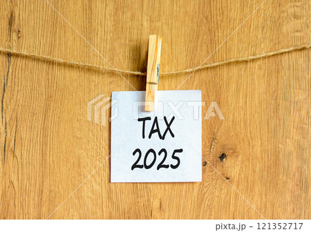 Planning tax 2025 new year symbol. Concept words Tax 2025 on beautiful white paper on wooden clothespin. Beautiful wooden background. Business tax 2025 new year concept. Copy space. Planning tax 2025 new year symbol. Concept words Tax 2025 on beautiful white paper on wooden clothespin. Beautiful wooden background. Business tax 2025 new year concept. Copy space. 121352717