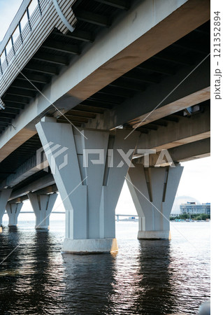 view from below of arches of suspension road. bridge over water, expressway against sky. 121352894