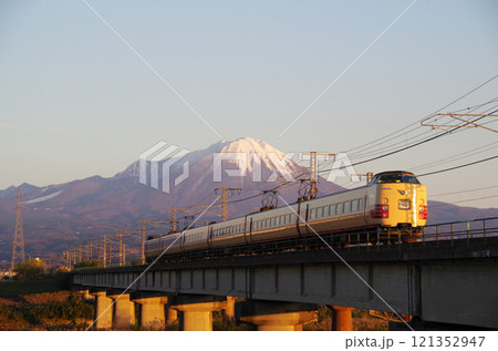 冠雪の大山の裾野に向かって日野川の橋梁を高速で駆け抜ける国鉄色381系特急やくも号リバイバル塗装車両 121352947