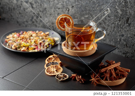 Cup of herbal tea with ingredients and slices of dried orange slices. 121353001