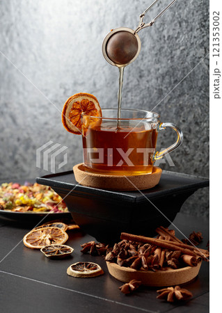 Cup of herbal tea with ingredients and slices of dried orange slices. 121353002
