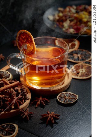 Cup of herbal tea with ingredients and slices of dried orange slices. 121353004