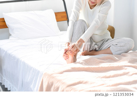 ベッドの上で足の痛みに悩むアジア人女性 ベッドの上で足の痛みに悩むアジア人女性 121353034