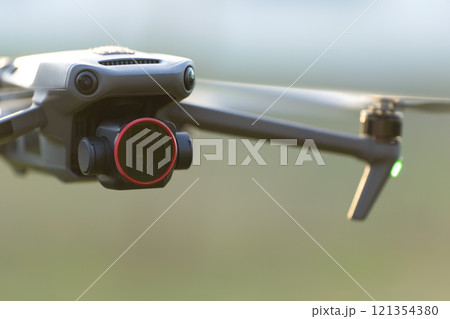 Drone with digital camera and fast rotating propellers flying taking video 121354380