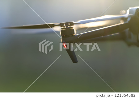 Drone aircraft with blurred fast rotating propellers and video camera flying in air 121354382
