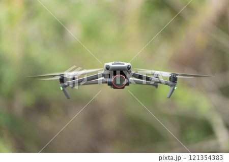 Drone aircraft with blurred fast rotating propellers and video camera flying in air 121354383