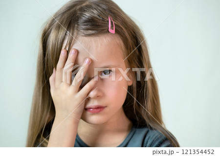 Close-up portrait of little child girl with long hair covering her mouth with hands. Close-up portrait of little child girl with long hair covering her mouth with hands. 121354452