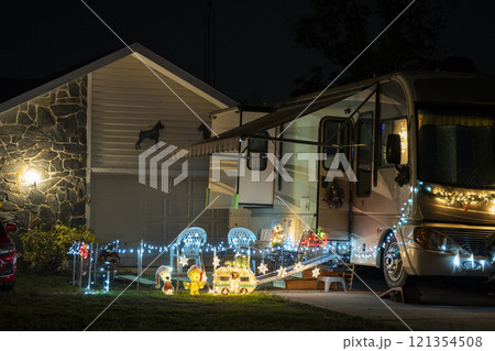 Brightly illuminated christmas decorations on front yard near camper van. Outside decor for winter holidays 121354508