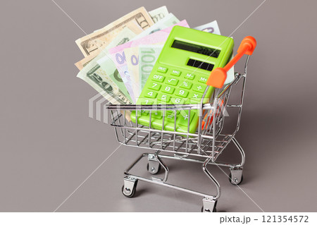 Shopping Cart trolley, Green Calculator, Money. Concept Inflation for Grocery Expenses, Consumerism. Cost of Living. Shopping Cart trolley, Green Calculator, Money. Concept Inflation for Grocery Expenses, Consumerism. Cost of Living. 121354572