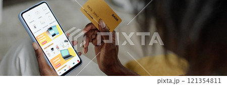 Website banner with unrecognizable woman holding golden credit card and choosing electronic device while doing shopping online Website banner with unrecognizable woman holding golden credit card and choosing electronic device while doing shopping online 121354811