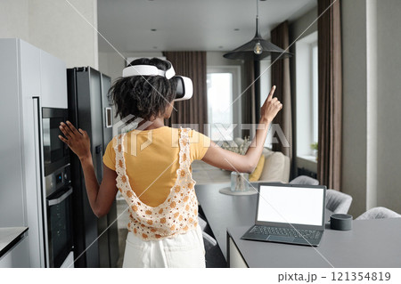 Back view of unrecognizable woman setting VR app for smart home while standing in kitchen Back view of unrecognizable woman setting VR app for smart home while standing in kitchen 121354819