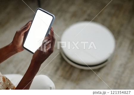 High angle shot of unrecognizable woman launching application for setting robot vacuum cleaner 121354827