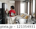 Elegant African American woman with gray laptop in hands standing near graphite fridge and setting smart refrigerator 121354931