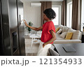 Side view shot of African American housewife leaning on velvet chair while setting system of smart fridge 121354933