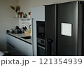 Black matte fridge with white tablet on its door in modern kitchen fully equipped with kitchen appliances 121354939
