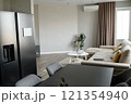 Modern dining area with graphite fridge and same colored table, light living room with comfortable couch and multicolored cushions 121354940