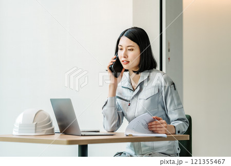 スマホで話す作業服姿の女性 121355467