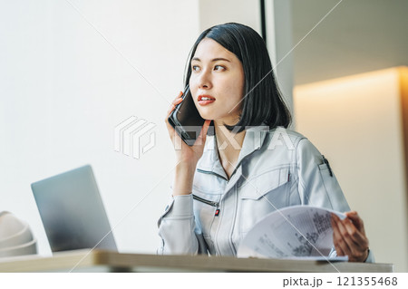 スマホで話す作業服姿の女性 スマホで話す作業服姿の女性 121355468