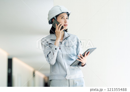 スマホで話す作業服を着た施工管理の若い女性 121355488