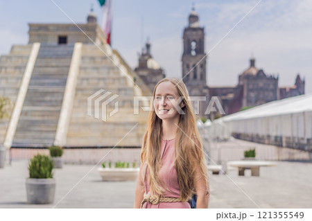 Woman tourist exploring the historic Zocalo square in Mexico City, standing in front of a replica Aztec pyramid with the Mexican flag waving in the background. The Metropolitan Cathedral can be seen Woman tourist exploring the historic Zocalo square in Mexico City, standing in front of a replica Aztec pyramid with the Mexican flag waving in the background. The Metropolitan Cathedral can be seen 121355549