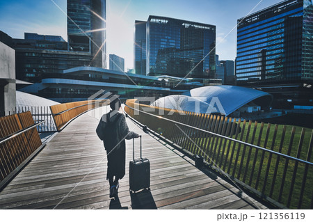 キャリーケースを持った女性旅行者の後ろ姿 121356119