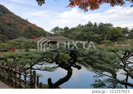 栗林公園、南湖の紅葉の楓岸から菊月亭を望む 121357025