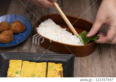 弁当箱にご飯やおかずを詰める手元 弁当箱にご飯やおかずを詰める手元 121357347