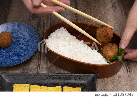弁当箱にご飯やおかずを詰める手元 121357349