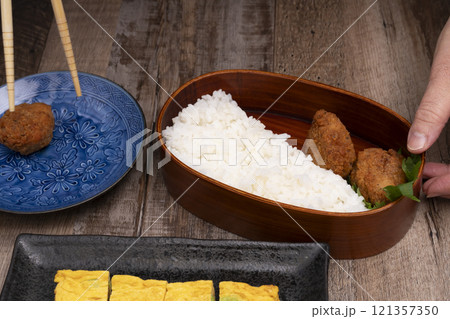 弁当箱にご飯やおかずを詰める手元 121357350
