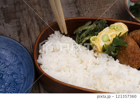 弁当箱にご飯やおかずを詰める手元 121357360