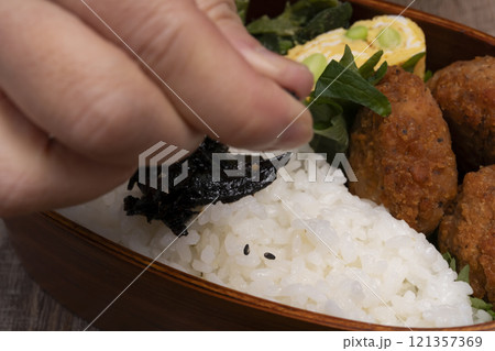 弁当箱にご飯やおかずを詰める手元 121357369