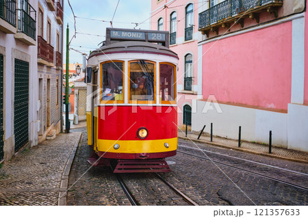 Famous vintage yellow tram 28 in the narrow streets of Alfama district in Lisbon, Portugal - symbol of Lisbon, famous popular travel destination and tourist attraction Famous vintage yellow tram 28 in the narrow streets of Alfama district in Lisbon, Portugal - symbol of Lisbon, famous popular travel destination and tourist attraction 121357633