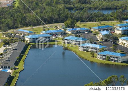 Apartment building roofs covered with blue protective tarp against rain water leaking until replacement of asphalt shingles. Damage done by hurricane winds 121358376