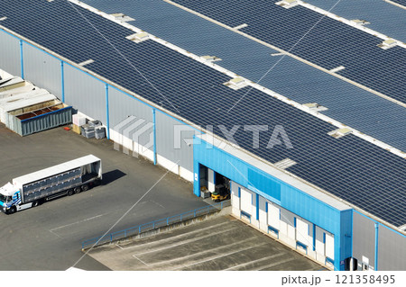 Aerial view of solar power plant with blue photovoltaic panels mounted on industrial building roof for producing green ecological electricity. Production of sustainable energy concept 121358495