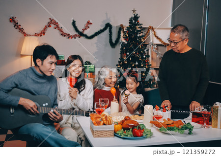 Multi-Generation Family Celebrate Christmas At Home Wearing Santa Hats And Antlers Opening Presents Multi-Generation Family Celebrate Christmas At Home Wearing Santa Hats And Antlers Opening Presents 121359272
