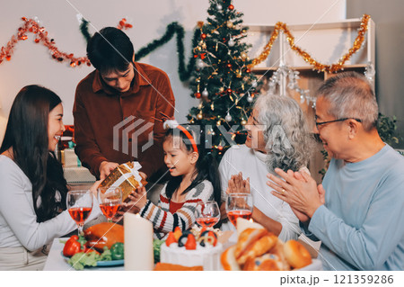 Portrait of Asian family exchanging presents during christmas at home. Attractive happy people holding gift box, celebrate holiday thanksgiving, xmas eve tradition in living room in house together. Portrait of Asian family exchanging presents during christmas at home. Attractive happy people holding gift box, celebrate holiday thanksgiving, xmas eve tradition in living room in house together. 121359286