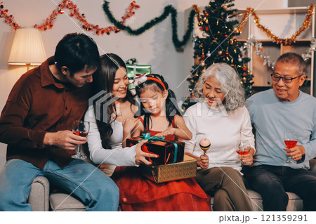 Portrait of Asian family exchanging presents during christmas at home. Attractive happy people holding gift box, celebrate holiday thanksgiving, xmas eve tradition in living room in house together. Portrait of Asian family exchanging presents during christmas at home. Attractive happy people holding gift box, celebrate holiday thanksgiving, xmas eve tradition in living room in house together. 121359291