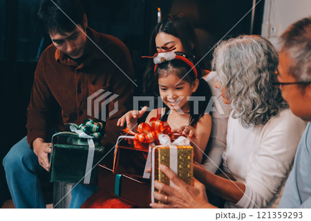 Portrait of Asian family exchanging presents during christmas at home. Attractive happy people holding gift box, celebrate holiday thanksgiving, xmas eve tradition in living room in house together. 121359293