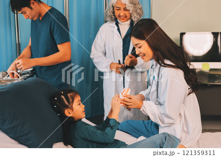 A team of doctors and nurses are working to treat a female patient in the patient's room. 121359311