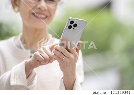 スマートフォンを操作するシニア女性の手元 121359341
