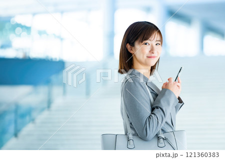 出勤するスーツを着た女性 明るいロビーを歩くOL 働くオフィスレディ 出勤するスーツを着た女性 明るいロビーを歩くOL 働くオフィスレディ 121360383