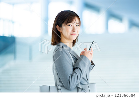 出勤するスーツを着た女性 明るいロビーを歩くOL 働くオフィスレディ 出勤するスーツを着た女性 明るいロビーを歩くOL 働くオフィスレディ 121360384
