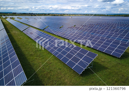 Aerial view of large sustainable electrical power plant with rows of solar photovoltaic panels for producing clean electric energy. Concept of renewable electricity with zero emission Aerial view of large sustainable electrical power plant with rows of solar photovoltaic panels for producing clean electric energy. Concept of renewable electricity with zero emission 121360796