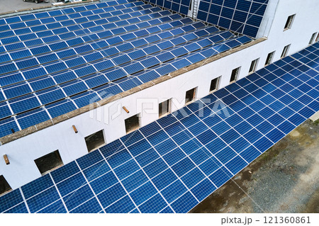 Aerial view of blue photovoltaic solar panels mounted on industrial building roof for producing green ecological electricity. Production of sustainable energy concept. 121360861