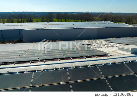 Aerial view of blue photovoltaic solar panels mounted on industrial building roof for producing green ecological electricity. Production of sustainable energy concept 121360863