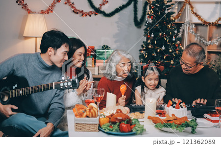 Multi-Generation Family Celebrate Christmas At Home Wearing Santa Hats And Antlers Opening Presents 121362089